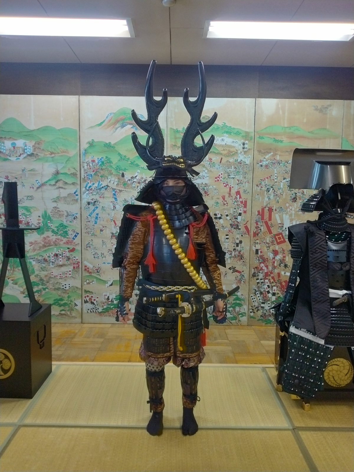 合戦図屏風を背に、甲冑試着体験