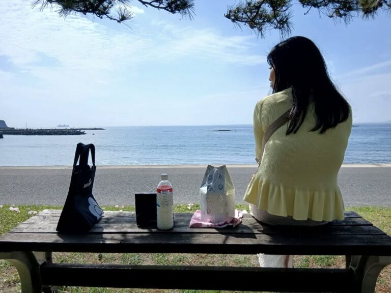 海辺のベンチで、ももの遺骨と一緒に海を眺める妻