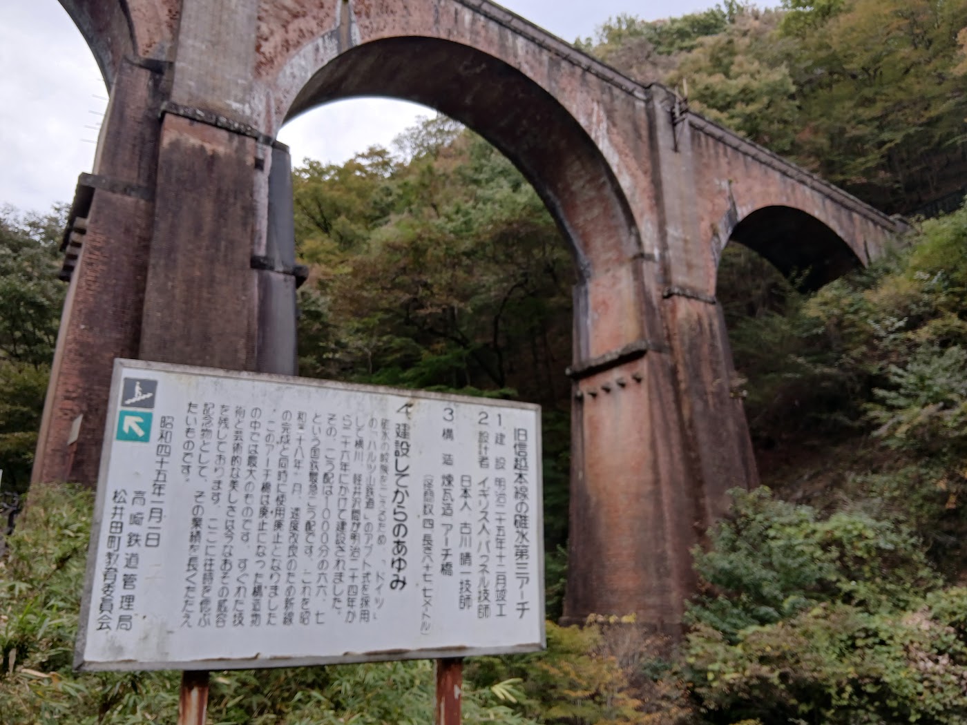 めがね橋の下に立つ説明板とアーチ